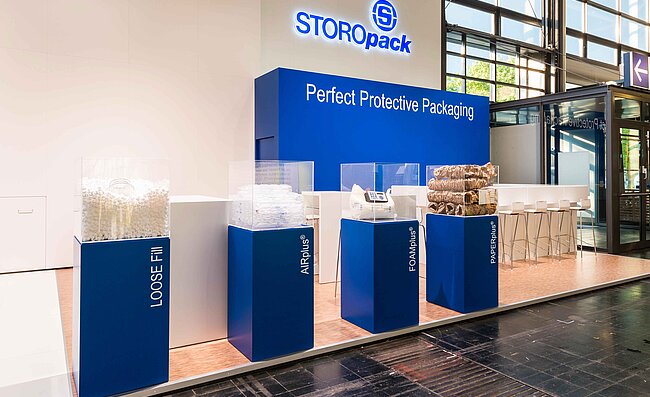 Ein Messestand von Storopack mit vier blauen Vitrinen