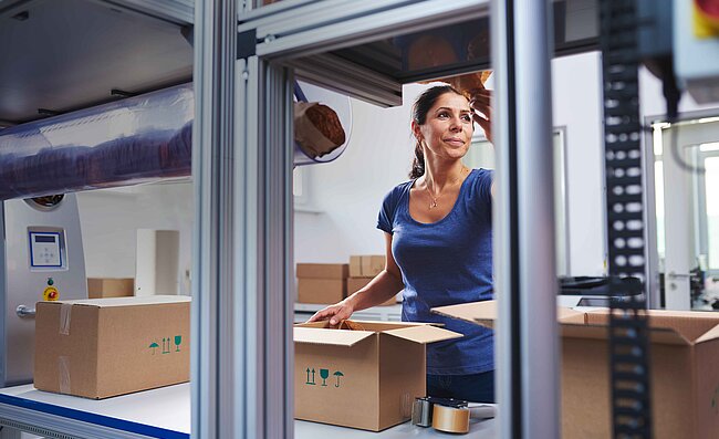 A woman packing products into a box at a packing station